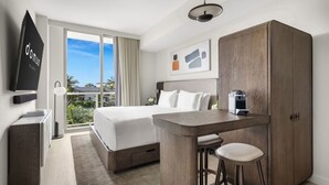 A hotel room with a bed, a desk with two stools, a wardrobe, a flat-screen TV, and a window with a view. - Domus Brickell Signature Studio (Miami)