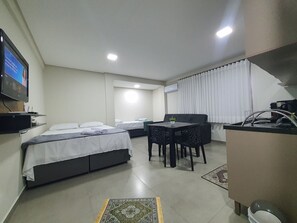 Une chambre d’hôtel comprenant un lit, une petite table à manger, un téléviseur et une kitchenette.