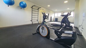 Ein Fitnessraum mit Trainingsgeräten, einer Klimmzugstange und zwei großen Trainingsbällen.
