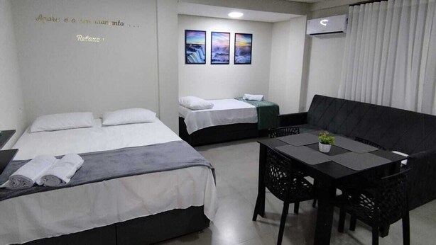 Ein Hotelzimmer mit zwei Betten, einem Esstisch und drei gerahmten Bildern an der Wand.