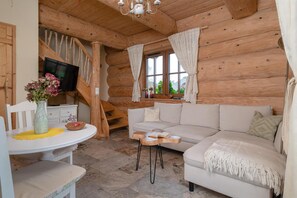 A cozy log cabin interior with a sofa, a dining table, and a TV mounted on the wall. - Comfortable Apartment, 2 Levels, Close to Beach (gmina Będzino)