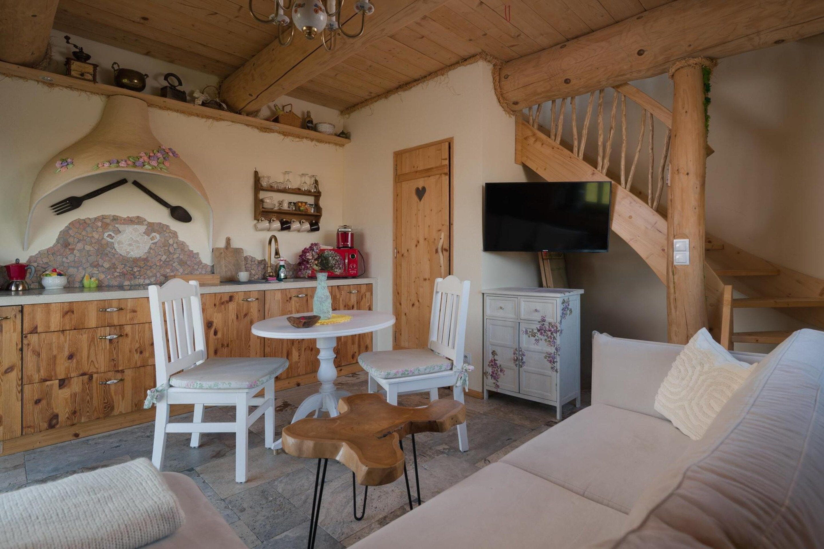 Un intérieur chaleureux avec un escalier en bois, un coin repas doté d’une table ronde et un canapé.