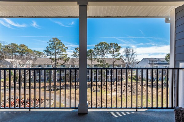 A covered balcony with a view of a residential area, including houses and trees. - Spacious 3BR Condo Centrally located. Enjoy Beach life here! (Rehoboth Beach)