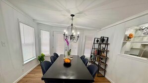 A dining room with a dark wooden table, six chairs, a chandelier, and a bookshelf. - Lake view, Cozy & Peaceful Townhouse w Covered Parking (Garland)