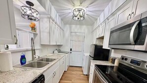 A modern kitchen with white cabinets, a stainless steel sink, a microwave, an oven, and a dishwasher. - Lake view, Cozy & Peaceful Townhouse w Covered Parking (Garland)