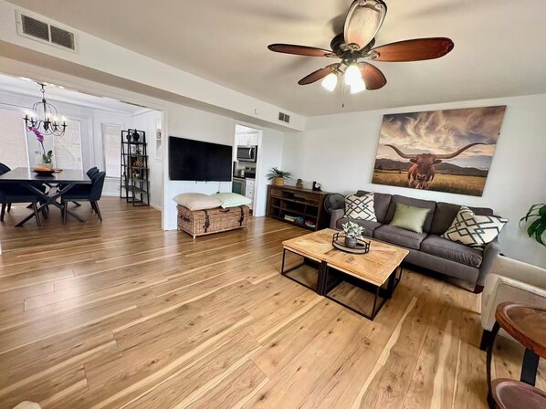 A spacious living area with a dining table, sofa, and a ceiling fan.