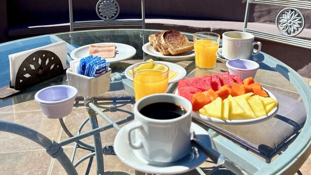 A breakfast table with food and drinks, set against a mountainous backdrop. - Hosteria Terrazas de la Posta (Purmamarca)