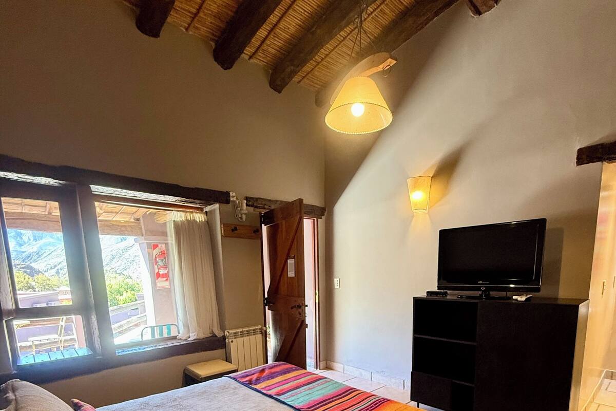 Une chambre à coucher avec un lit, une télévision, une fenêtre donnant sur un beau paysage et un plafond en bois.