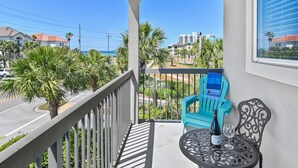 A balcony with a view of the ocean, a chair, a table, and a bottle of wine. - Alerio D301 (Miramar Beach)