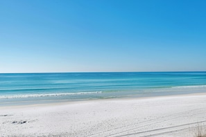Ein Strand mit klarem, blauem Wasser und weißem Sand.