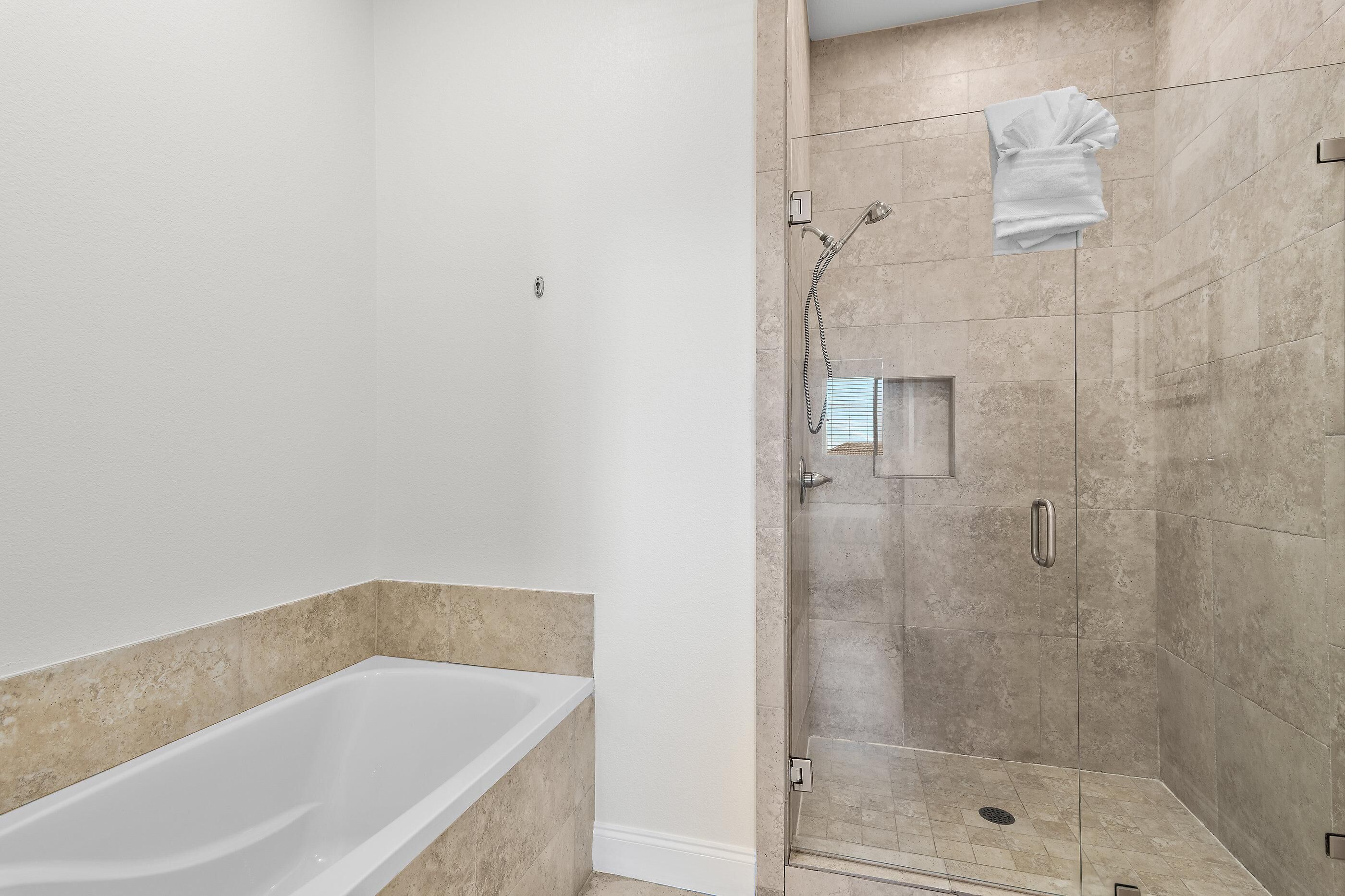 Une salle de bain moderne avec une baignoire, une douche à parois de verre et des carreaux de couleur beige.