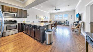 A modern kitchen with a central island, stainless steel appliances, and a dining area with a view. - Alerio D301 (Miramar Beach)