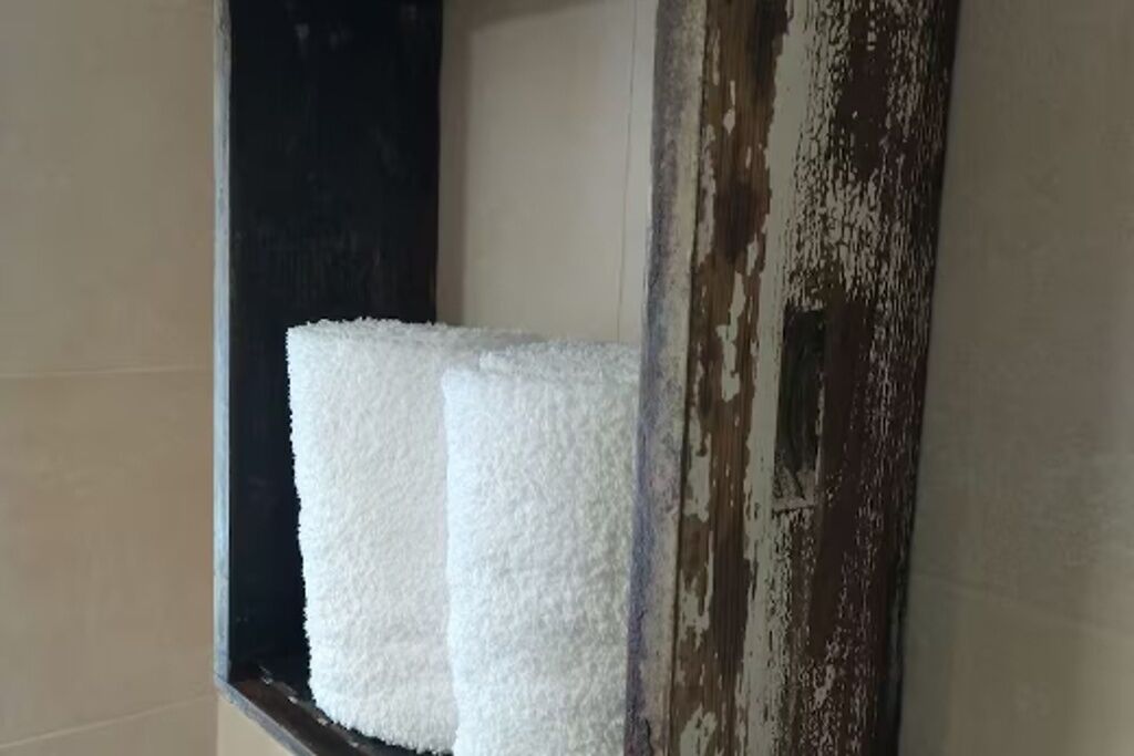 A window with a white textured object, possibly a towel or decorative item, and a weathered wooden frame.