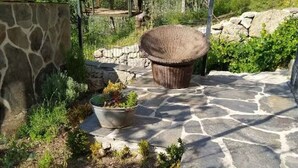 Een terras van stenen met een grote gevlochten mand en een bloempot.