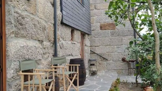 Een gebouw van steen met een donker dak, terras en een kleine tuin.