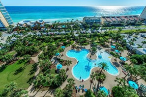 Un complexe hôtelier doté d’une grande piscine, de palmiers et offrant une vue sur l’océan.