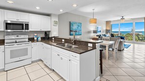 A modern kitchen with white cabinets, a stainless steel microwave, and a granite countertop. - Sterling Shores 408 (Destin)
