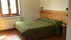 A room with two beds, a window, a radiator, and a wooden headboard. - Agriturismo Fiorella (Celico)
