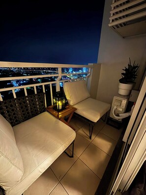 A balcony with two chairs, a small table with a lantern, and a potted plant. - Cozy staycation in Quezon City (Quezon City)