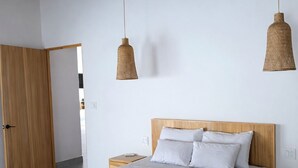 A modern bedroom with a wooden bed frame, a ceiling fan, and two hanging light fixtures. - Stylish 3BR Villa w/ Pool at Marino Ballena (Uvita)