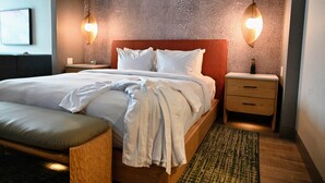 A hotel room with a large bed, two bedside tables, a wooden bench, a patterned wall, and two pendant lights. - The Mindaro, part of JdV by Hyatt (Portland)