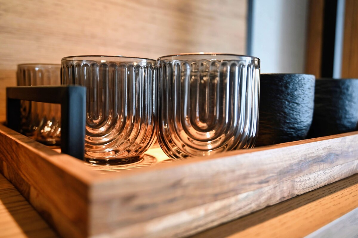Una bandeja de madera con varios vasos transparentes de diseño acanalado.
