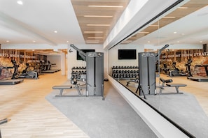 A gym with exercise equipment, a wall-mounted TV, and a mirror reflecting the space. - The Mindaro, part of JdV by Hyatt (Portland)