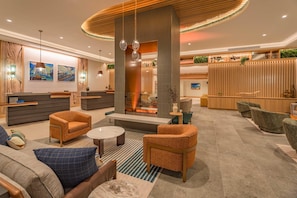 A modern hotel lobby with a reception desk, seating area, and a fireplace. - The Mindaro, part of JdV by Hyatt (Portland)