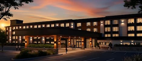 A modern hotel with a covered entrance, multiple floors, and a parking lot.