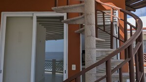 Eine Wendeltreppe mit Metallgeländer, die zu einem Balkon mit Meerblick führt.