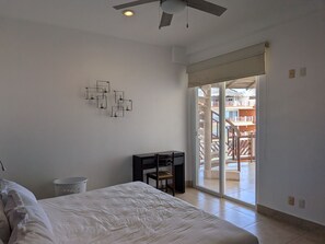 A bedroom with a bed, a desk, a chair, a ceiling fan, and a sliding glass door leading to an outdoor area. - 3 Bdm 2 Storey Penthouse Palapa Ocean View (Bajos de Chila)