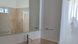 Ein Badezimmer mit einer beigen Arbeitsplatte, einem runden Waschbecken, einem Spiegel, einer Toilette und einer Duschvorhang.