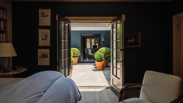 A room with a bed, a chair, a desk, and a view of a garden through open doors. - Private Hollywood Hills View Estate 4BR (Los Angeles)
