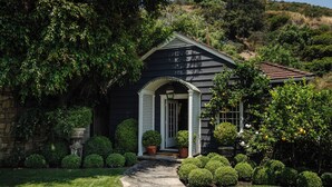 A house with a stone pathway leading to a white door, surrounded by well-maintained bushes and trees. - Private Hollywood Hills View Estate 4BR (Los Angeles)