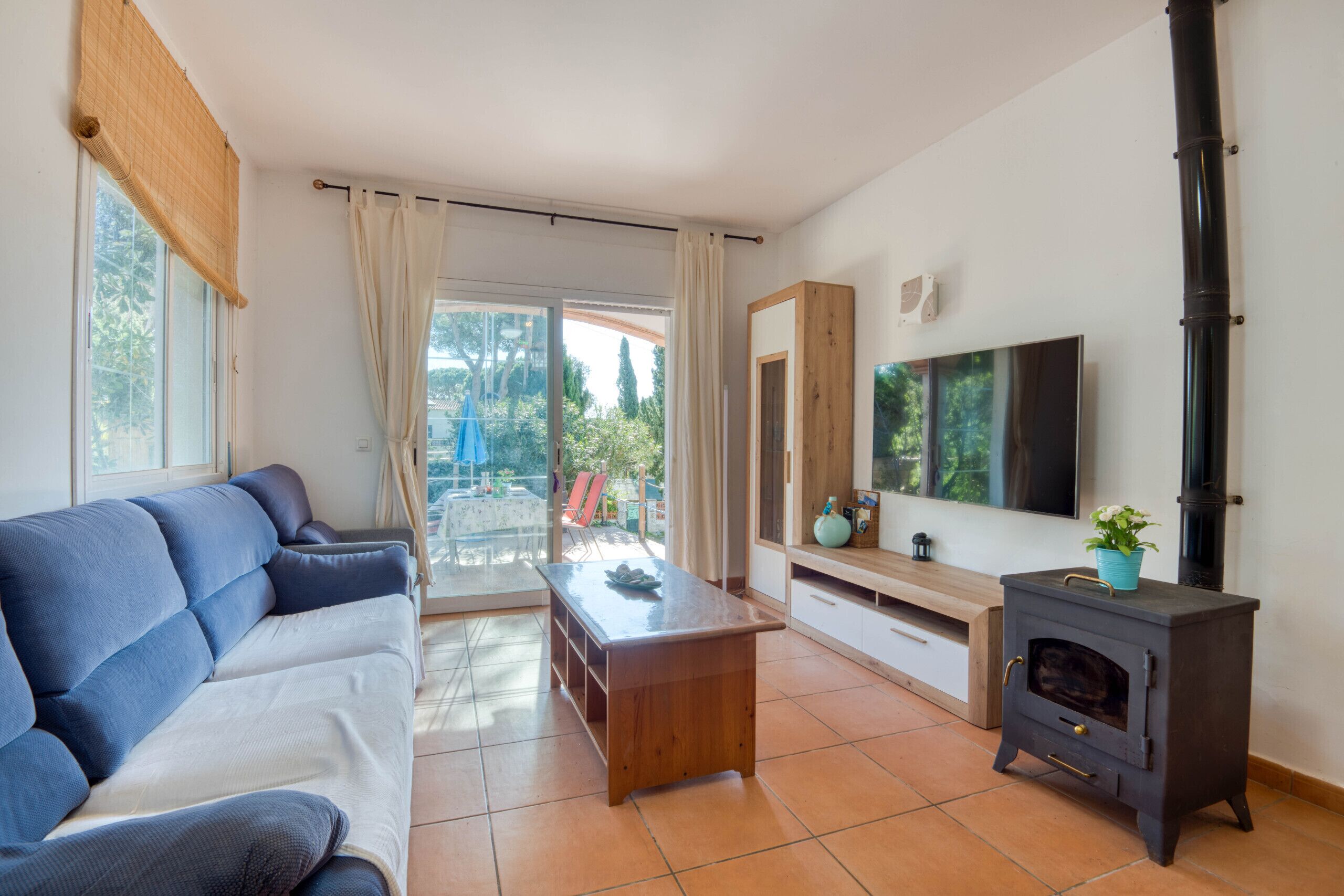 A living room with a sofa, a coffee table, a TV, a fireplace, and a sliding glass door leading to an outdoor area.