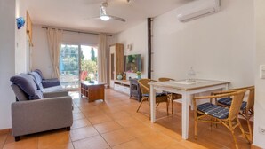 Un salon comprenant un canapé, une table à manger, des chaises et un téléviseur.