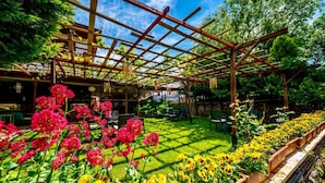 Un jardin agrémenté d’une pergola, d’un espace salon extérieur et de parterres de fleurs.