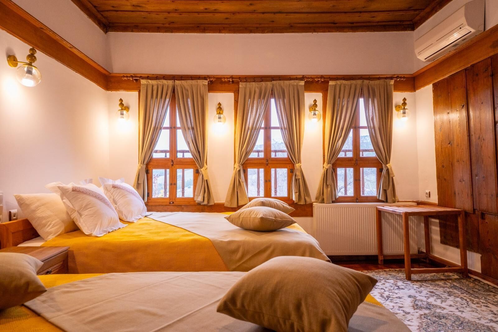 A hotel room with two beds, wooden beams, a radiator, and a small table.