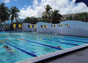 A swimming pool with multiple lanes, palm trees, and a clear sky. - South Beach Ocean Drive Condo w/ Full Kitchen – Walk to Beach (Miami Beach)
