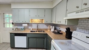 A kitchen with light green cabinets, a white dishwasher, a white stove, and a tiled backsplash. - Near Sherman College 2BR w/ Wi-Fi + Washer/Dryer (Boiling Springs)