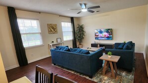 A living room with a sofa, a coffee table, a TV, and a ceiling fan. - Near Sherman College 2BR w/ Wi-Fi + Washer/Dryer (Boiling Springs)