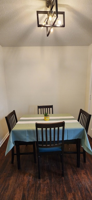Un espace repas comprenant une table, des chaises et un luminaire suspendu au plafond.