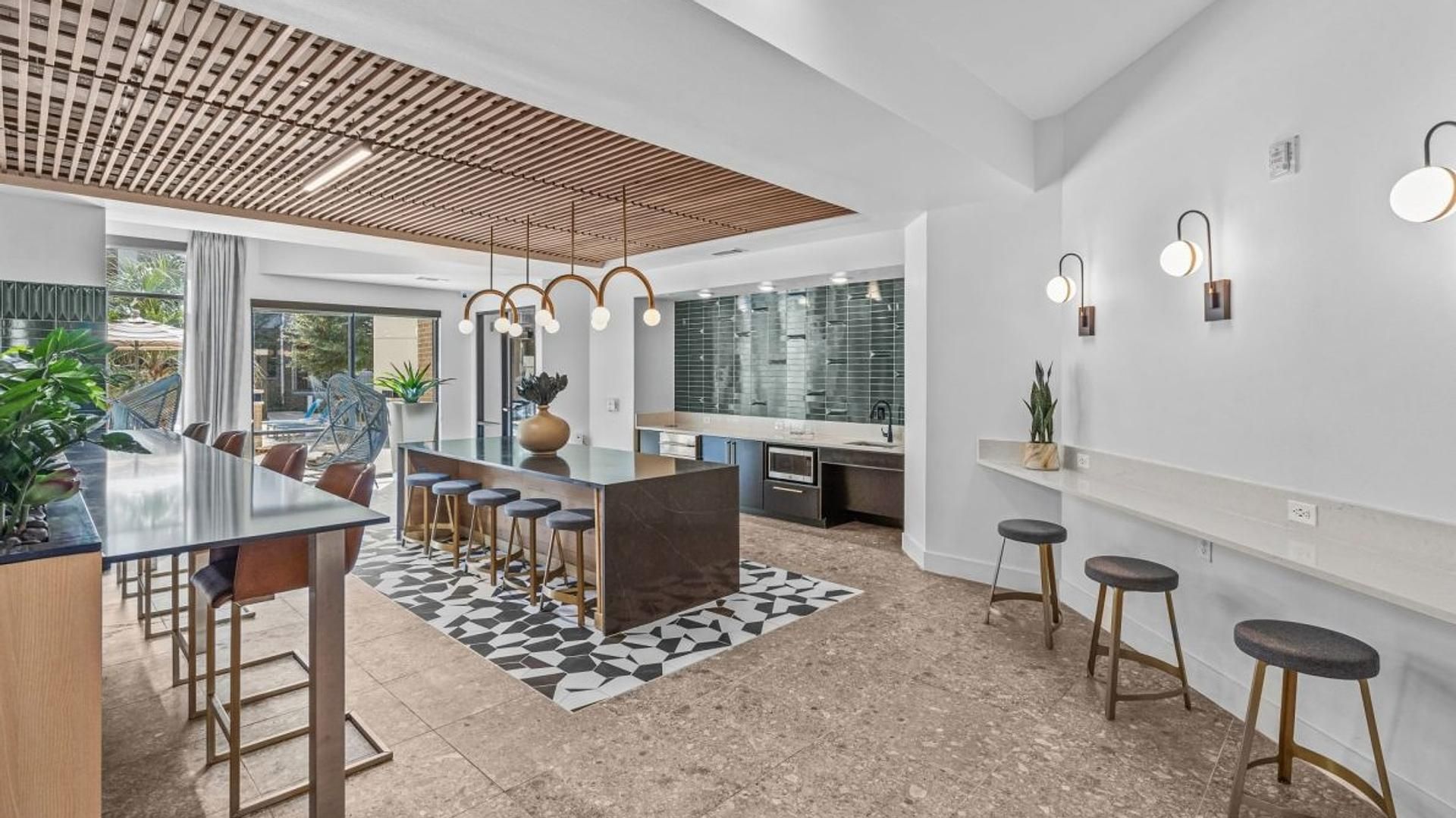 Uma cozinha moderna com ilha central, banquetas e iluminação pendente.
