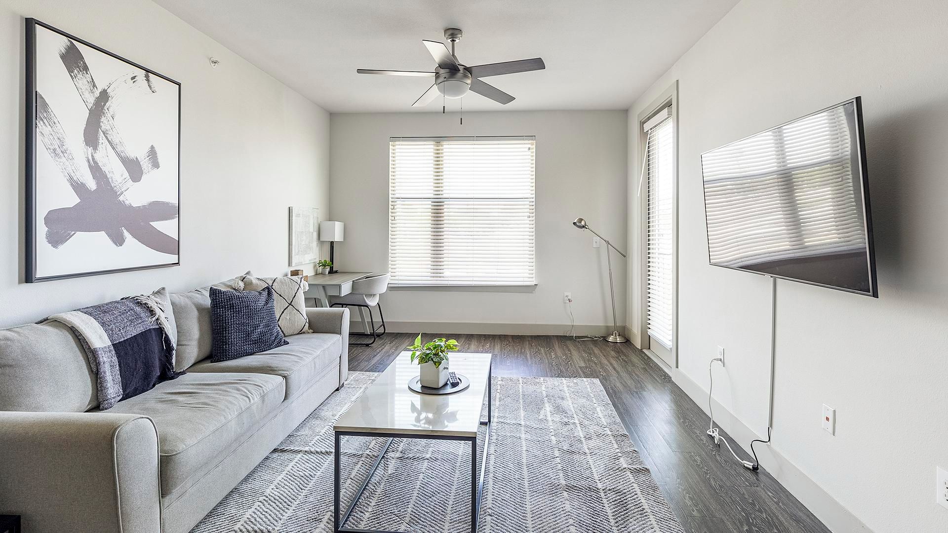 A modern living room with a sofa, coffee table, and a ceiling fan.