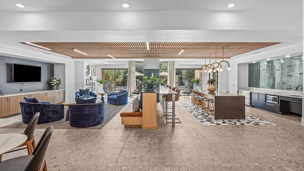 A spacious living area with a large dining table, comfortable seating, and a kitchen area with modern appliances. - Landing Apartments Midtown Park (Dallas)