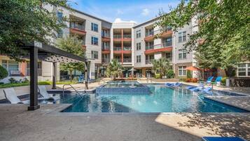 Un edificio residencial de varios pisos con piscina central, zona de estar al aire libre y un patio cubierto.