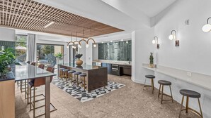 A modern kitchen with a central island, bar stools, and pendant lighting. - Landing Apartments Midtown Park (Dallas)