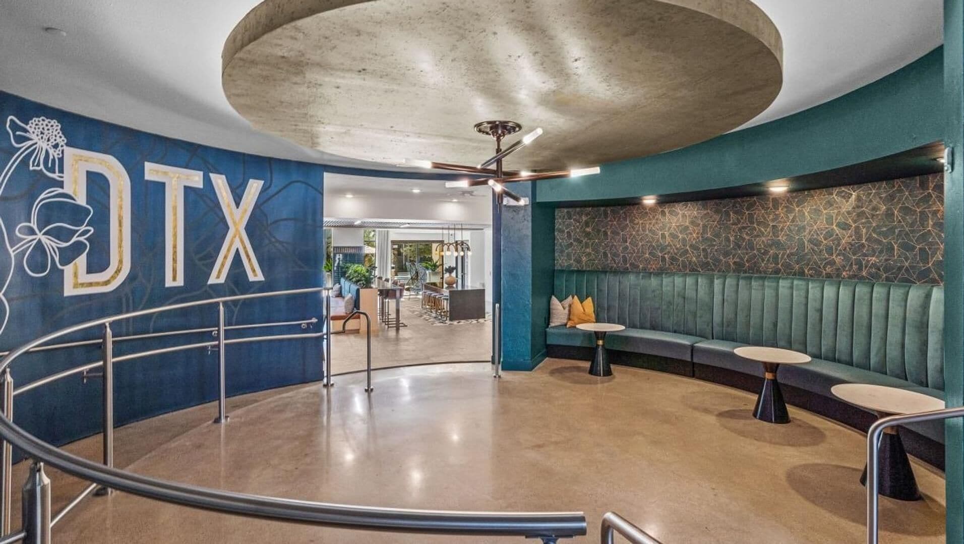 A modern interior with a curved staircase, a seating area with a stone wall, and a ceiling with a central light fixture.