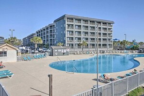 Ein Hotel mit Schwimmbad, mehreren Balkonen und einem Parkplatz.