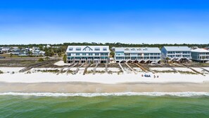 Ein Strandhotel mit mehreren Etagen, einer Promenade, die zum Strand führt, und freiem Blick auf das Meer.